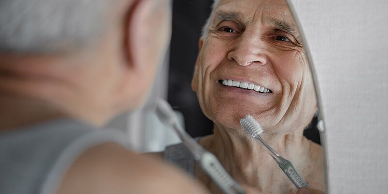 Alter Mann putzt sich seine Zähne.
