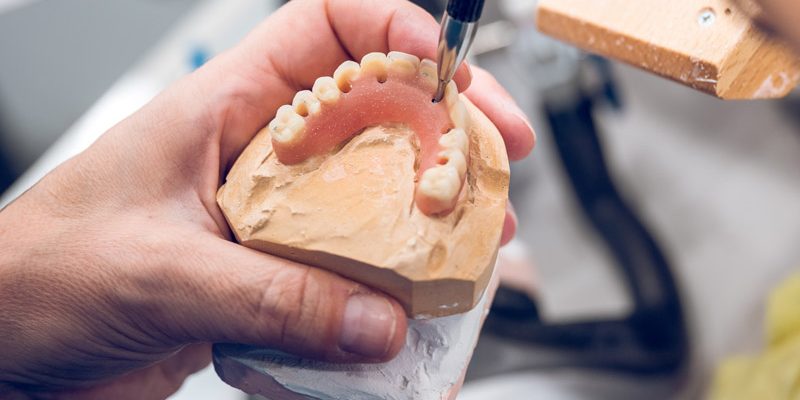 crop-dental-technician-carving-denture-while-worki-2022-01-31-16-13-47-utc-web