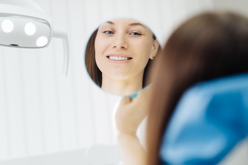dentist-hands-and-happy-patient-looking-in-mirror-2021-09-15-19-38-05-utc dentist-hands-and-happy-patient-looking-in-mirror-2021-09-15-19-38-05-utc