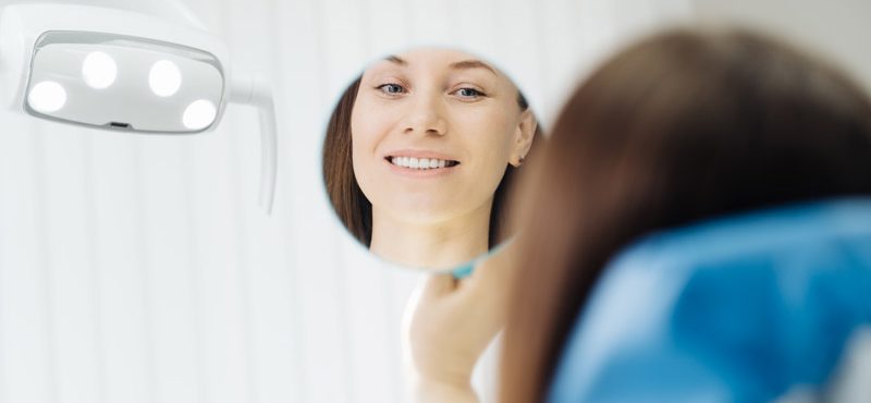dentist-hands-and-happy-patient-looking-in-mirror-2021-09-15-19-38-05-utc