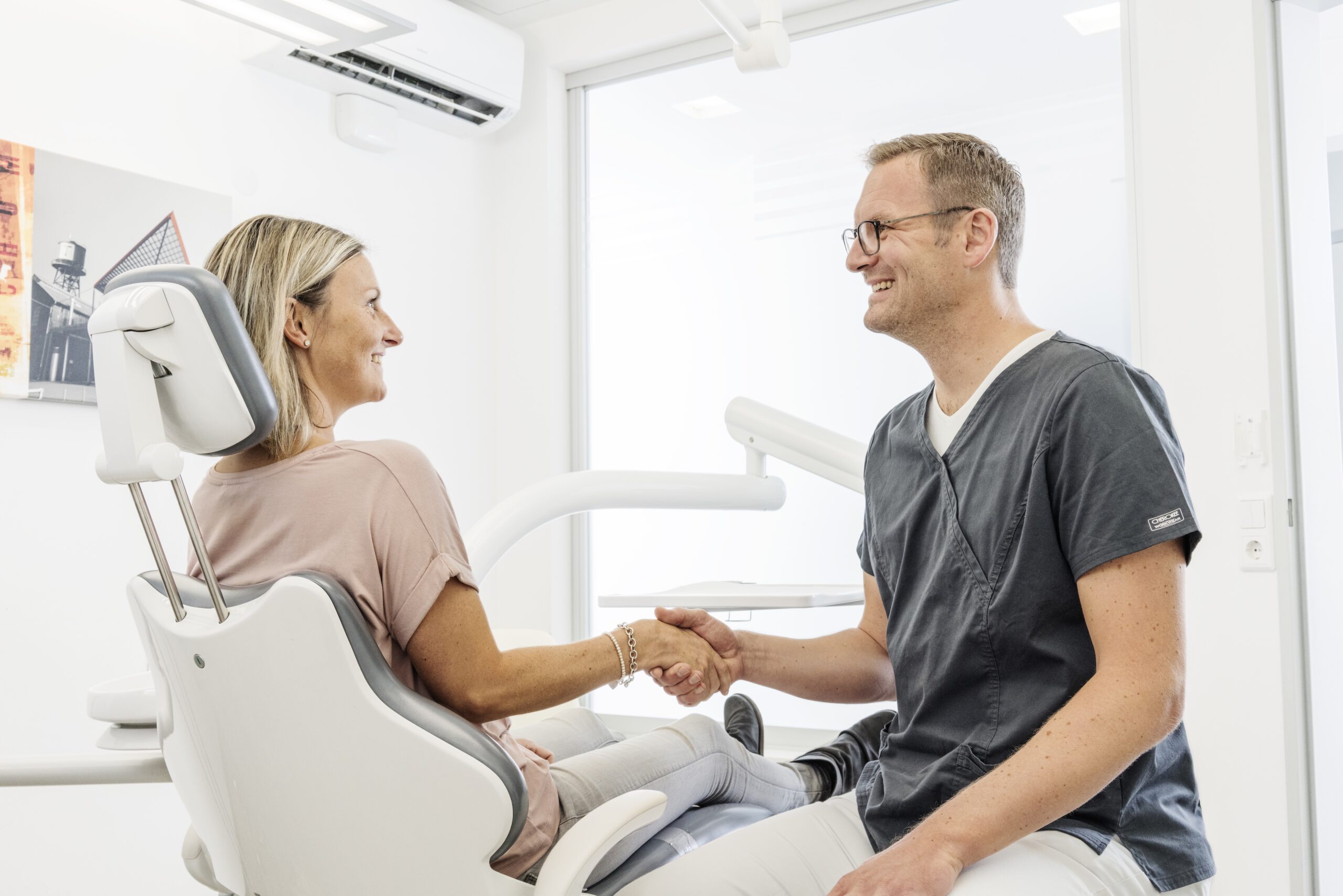 Zahnarzt begrüßt Patientin in der modernen Praxis der vor-Ort-Zahnärzte in Bochum.